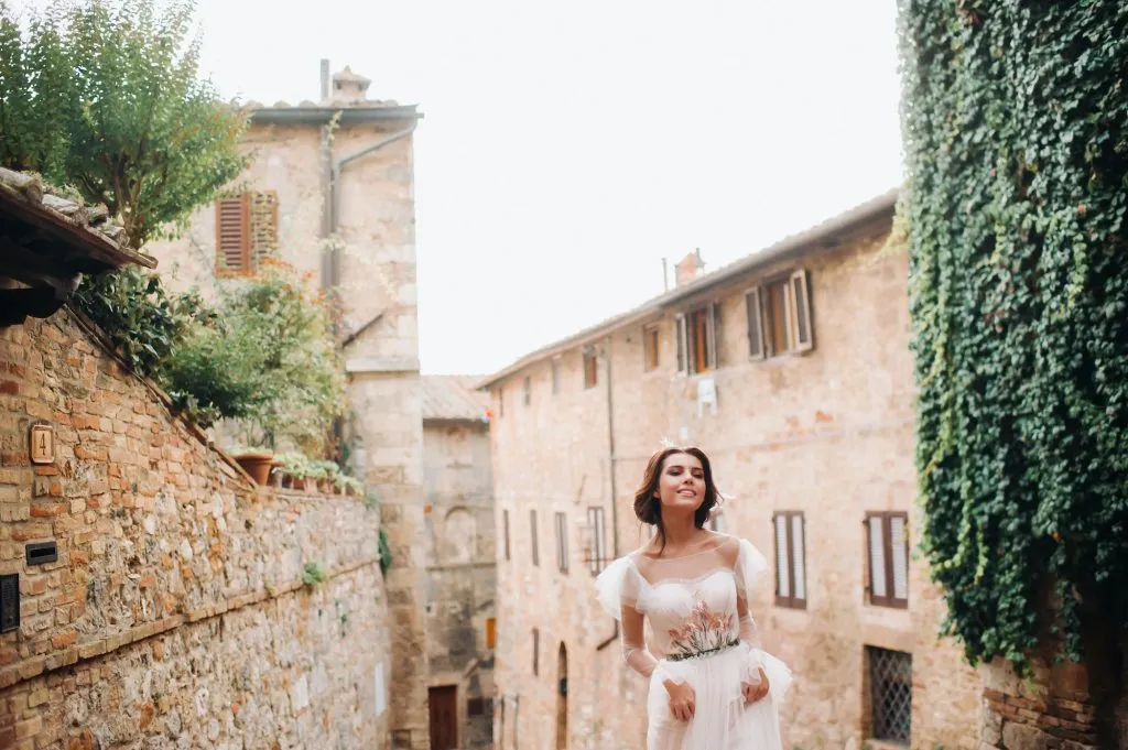 A bride in a white dress in the old town of San Gimignano.A girl walks around the city in Italy