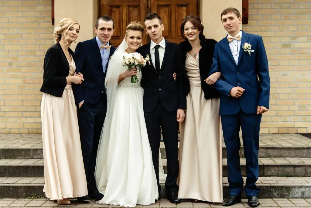 bride and groom with happy groomsman and bridesmaid posing at church