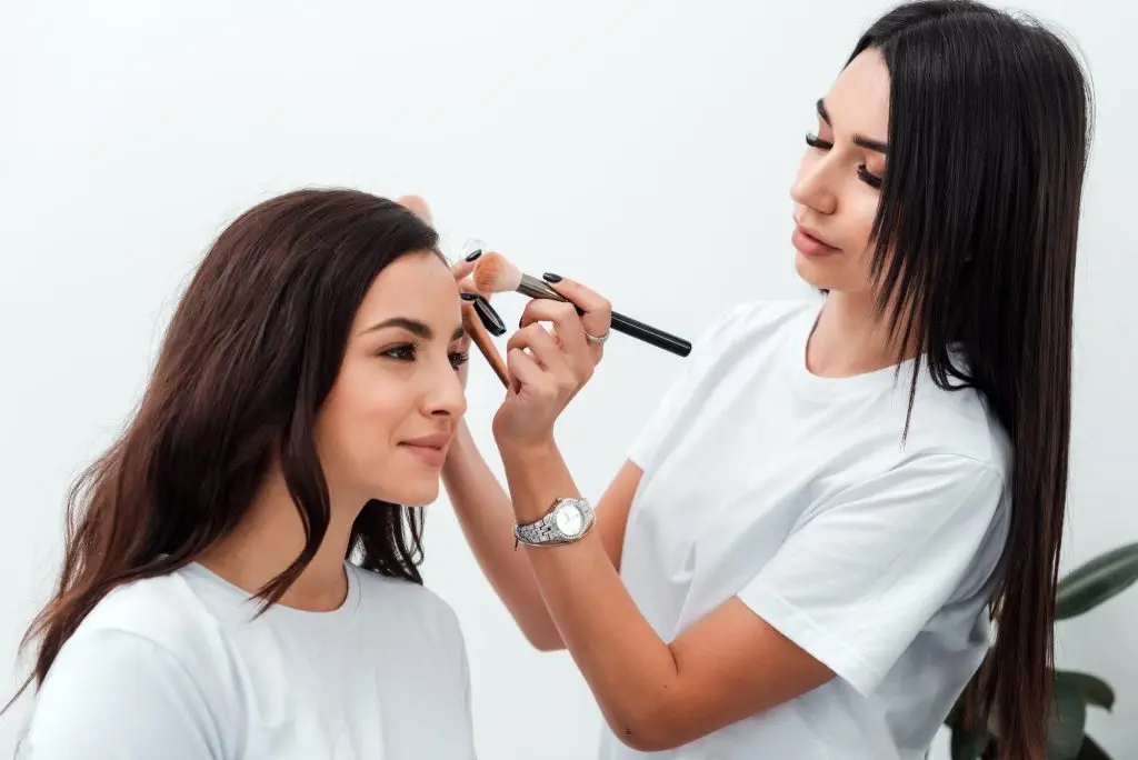 Make up artist doing professional make up of young woman