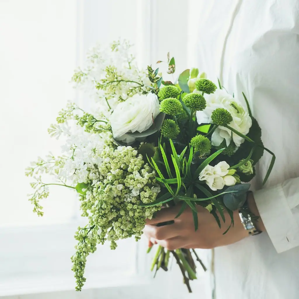 Young woman wearing white clothes holding flowers bouquet. Wedding concept