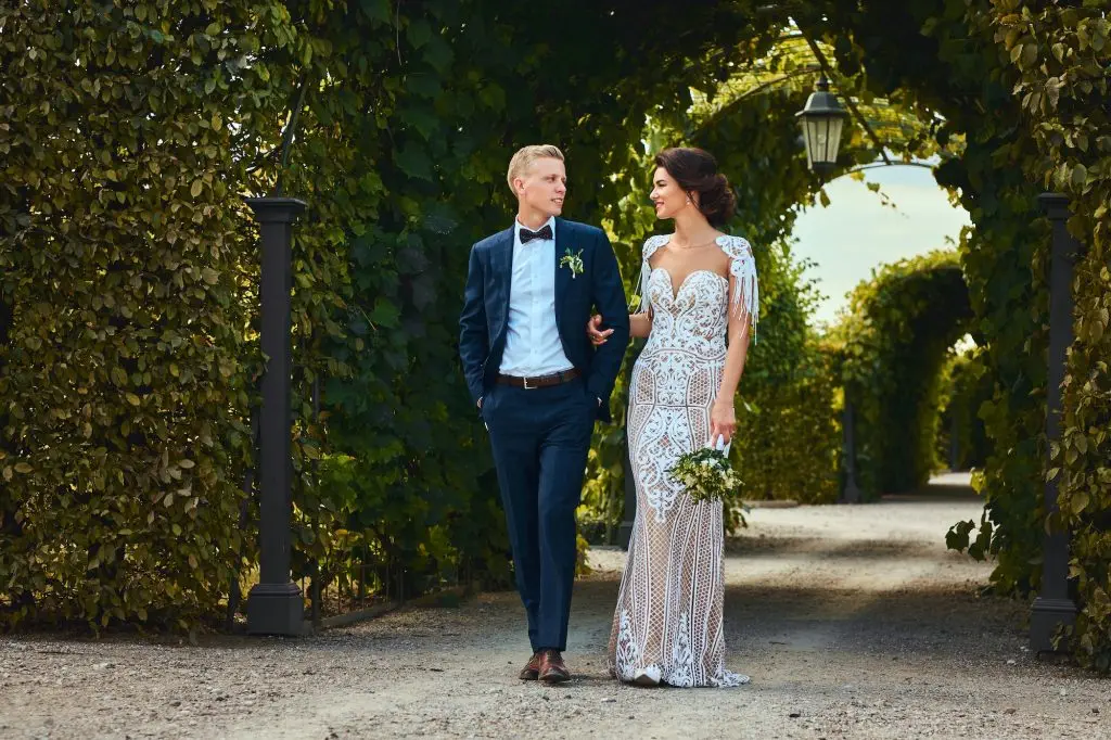Happy wedding couple is walking by the amazing garden.