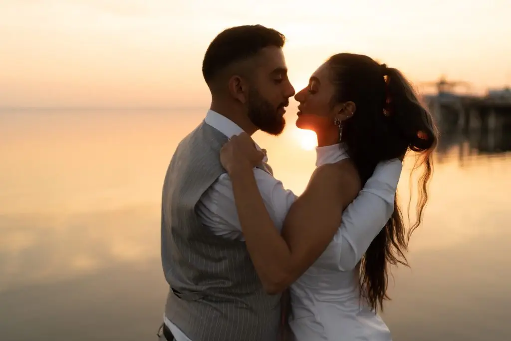 Loving couple enjoy sunset standing in shallow lake water