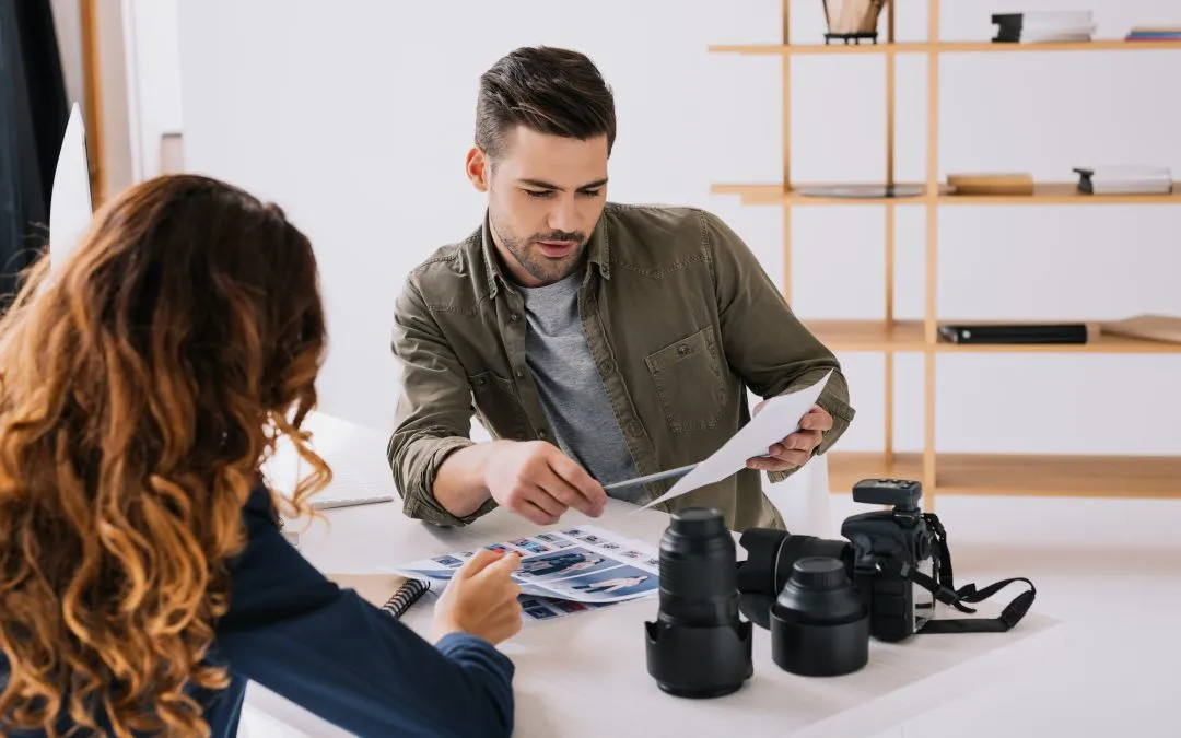 male photographer and model choosing photos for portfolio in modern office