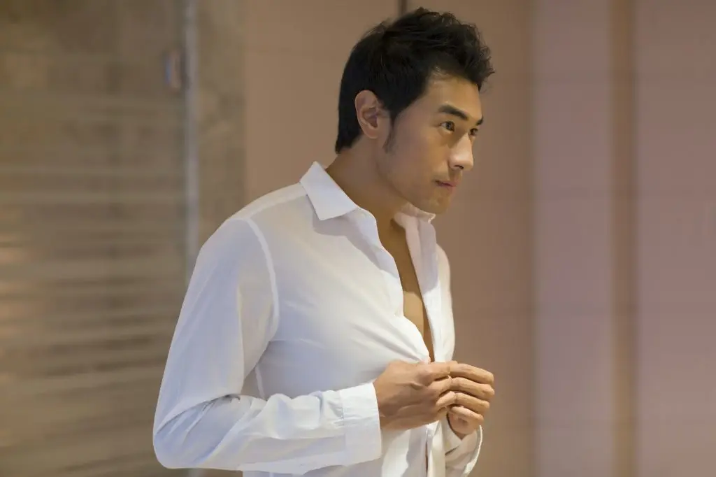 Young man buttoning shirt