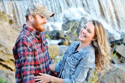 Happy newly engaged couple laughing during photo shoot for engagement photos