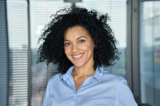 Headshot portrait of stylish African American businesswoman in modern office.